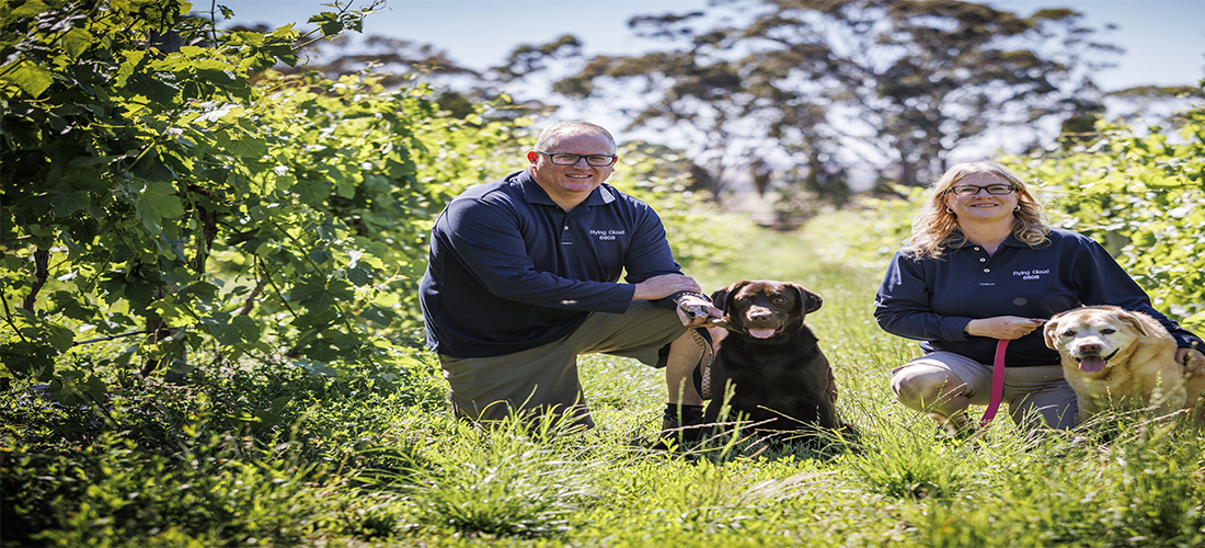 Winery owners in field with two dogs